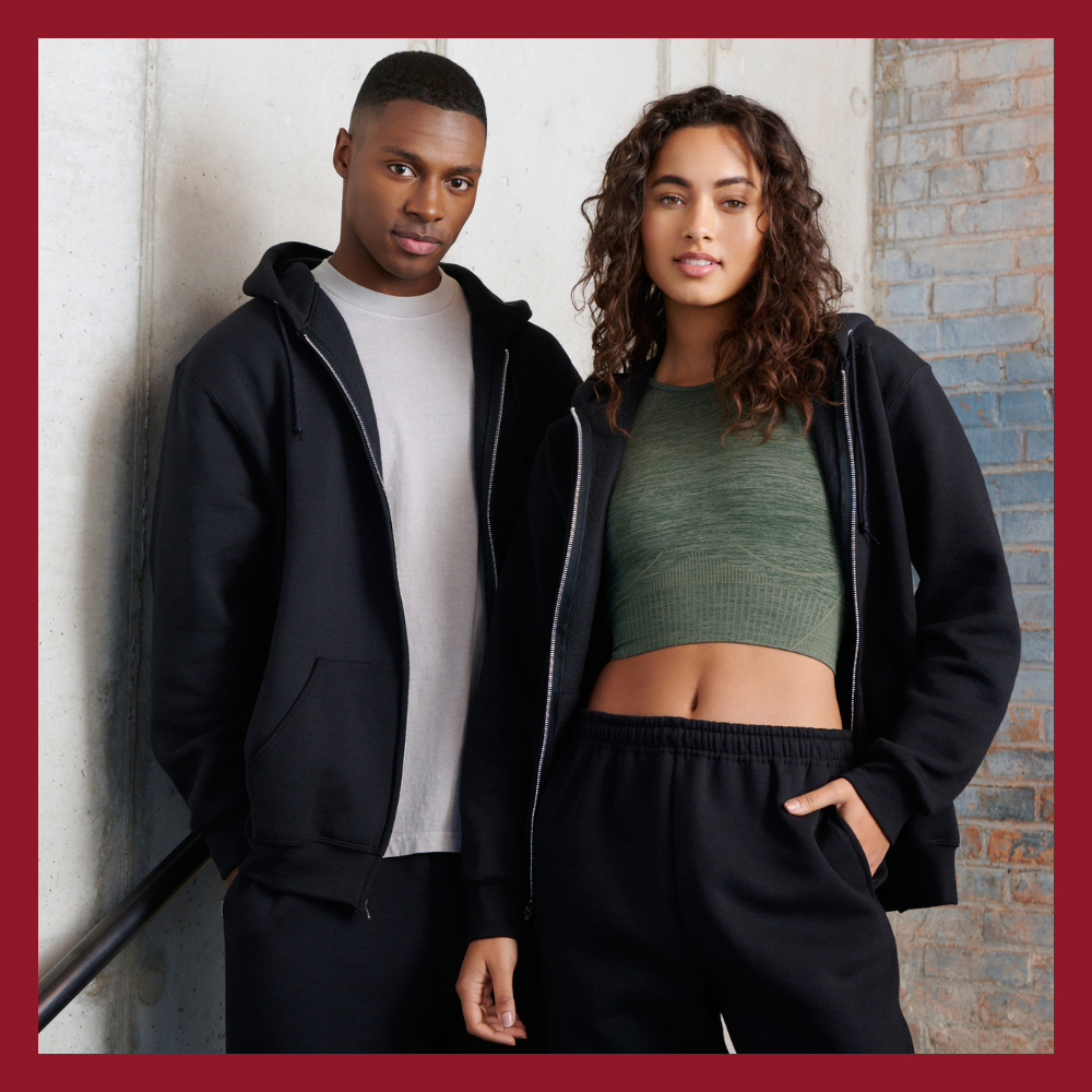 male model wearing white t-shirt, black zip hoodie sweatshirt and black sweatpants, female model wearing green top, black zip hoodie sweatshirt and black sweatpants